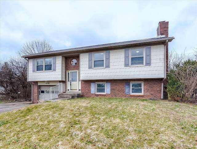 raised ranch with aphalt driveway, brick siding, a chimney, a garage, and a front lawn