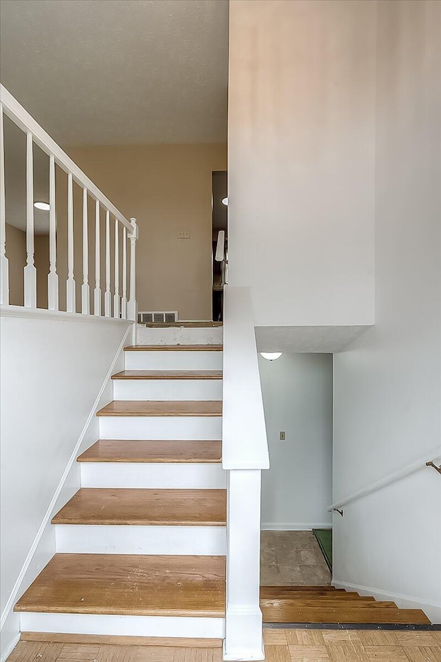 staircase featuring wood finished floors and visible vents