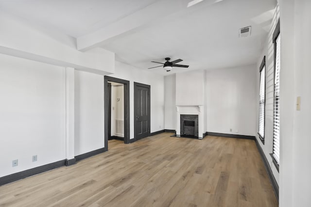 unfurnished living room featuring baseboards, a ceiling fan, light wood-style flooring, a fireplace, and beam ceiling