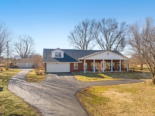 view of front facade with a garage, brick siding, roof with shingles, covered porch, and a front yard