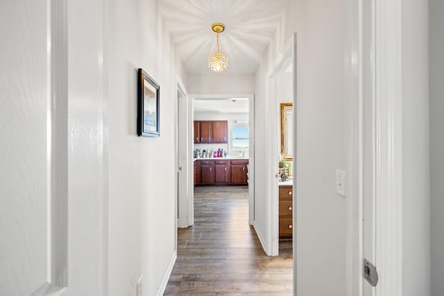 corridor featuring baseboards, dark wood finished floors, and a sink