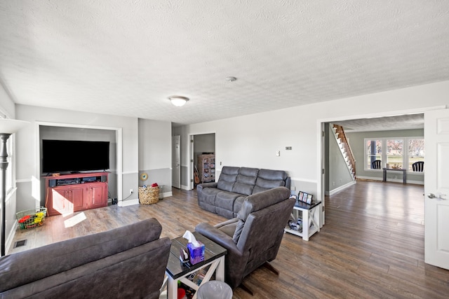 living area featuring a textured ceiling, stairs, baseboards, and wood finished floors