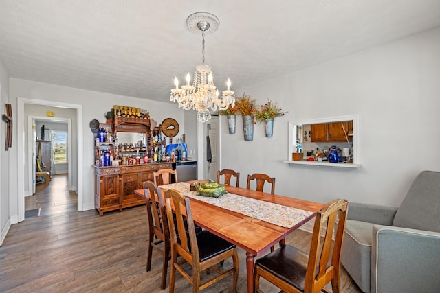 dining area featuring a bar, an inviting chandelier, baseboards, and dark wood-style flooring