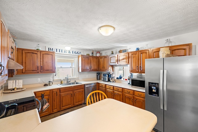 kitchen featuring brown cabinetry, appliances with stainless steel finishes, light countertops, under cabinet range hood, and a sink