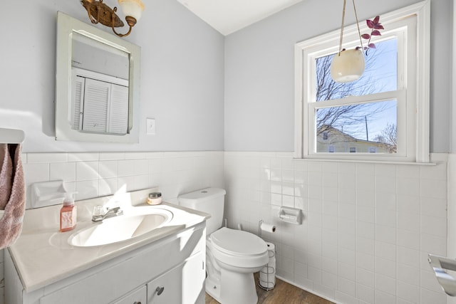 bathroom with a wainscoted wall, tile walls, toilet, vanity, and wood finished floors