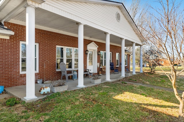 exterior space featuring brick siding, a lawn, and a porch