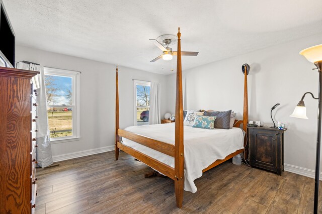 bedroom with multiple windows, baseboards, dark wood finished floors, and a ceiling fan