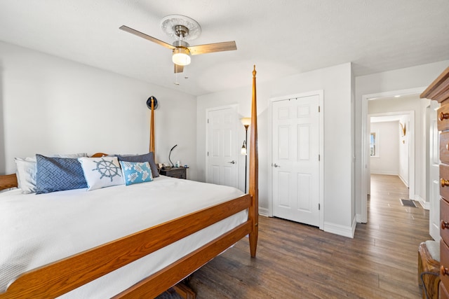 bedroom featuring dark wood-style floors, baseboards, visible vents, and a ceiling fan