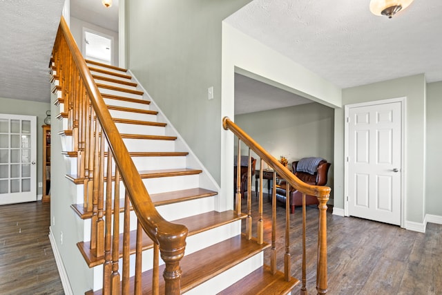 stairs with a textured ceiling, baseboards, and wood finished floors