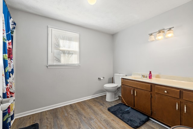 bathroom with toilet, baseboards, wood finished floors, and vanity