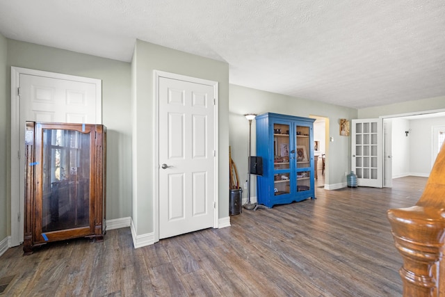 interior space with a textured ceiling, baseboards, and wood finished floors