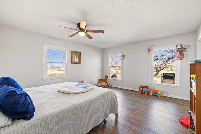 bedroom with a ceiling fan, a textured ceiling, baseboards, and wood finished floors