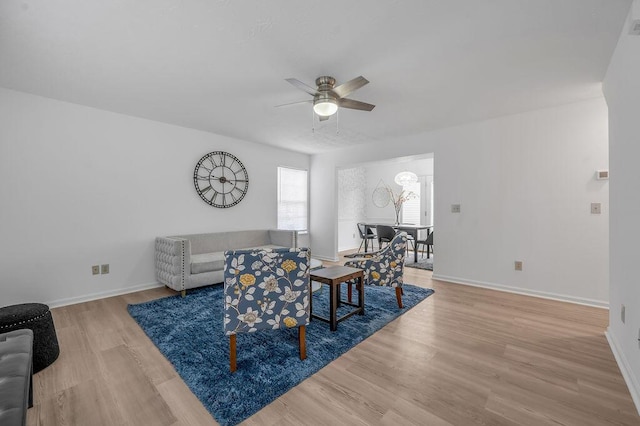 living area with ceiling fan, baseboards, and wood finished floors