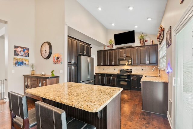 kitchen featuring light stone counters, a kitchen island, dark wood-style flooring, a sink, and black appliances