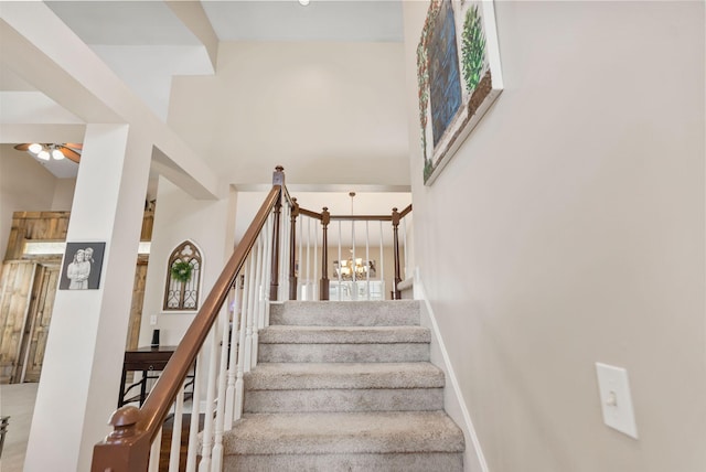 staircase featuring ceiling fan with notable chandelier and baseboards