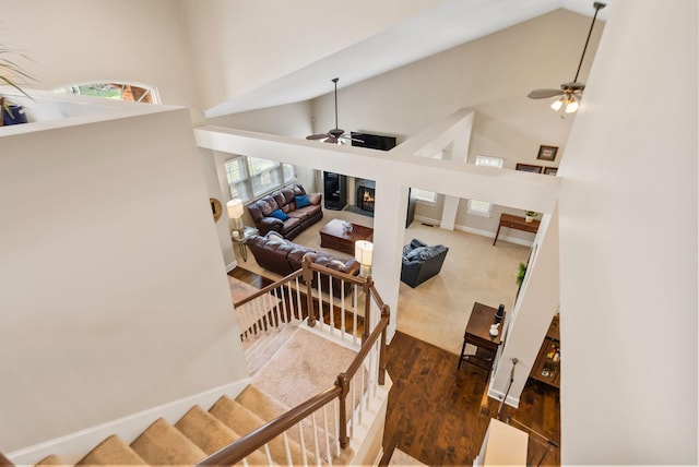 stairs with baseboards, high vaulted ceiling, ceiling fan, and wood finished floors