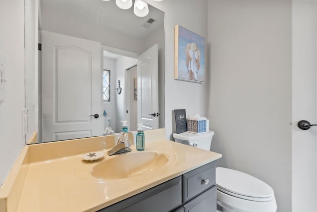 bathroom with vanity, toilet, and visible vents