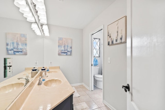 bathroom with a sink, toilet, double vanity, and tile patterned floors