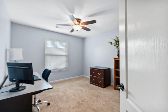 office space featuring baseboards, a ceiling fan, visible vents, and light carpet