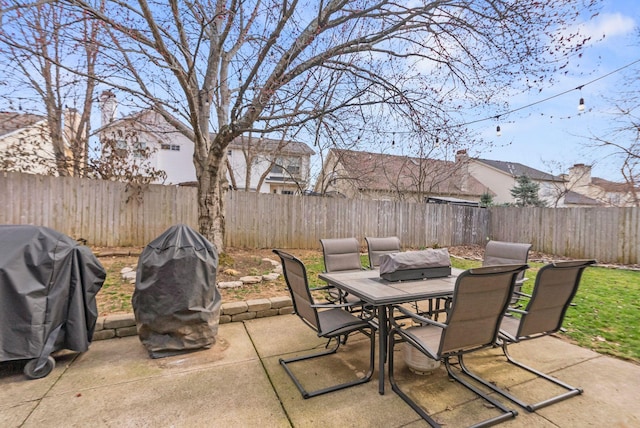 view of patio with area for grilling, outdoor dining area, and a fenced backyard