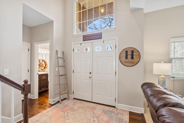 entryway with a towering ceiling, baseboards, and wood finished floors