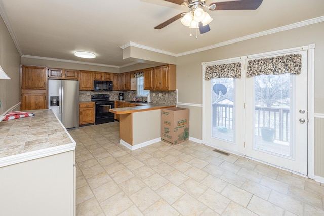 kitchen with black appliances, tasteful backsplash, a peninsula, and brown cabinets