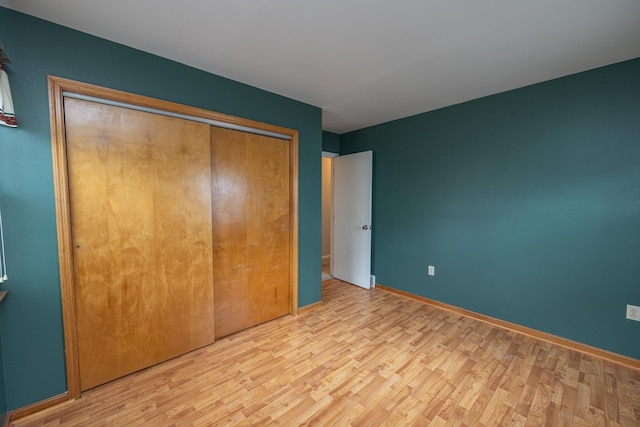 unfurnished bedroom featuring a closet, baseboards, and wood finished floors