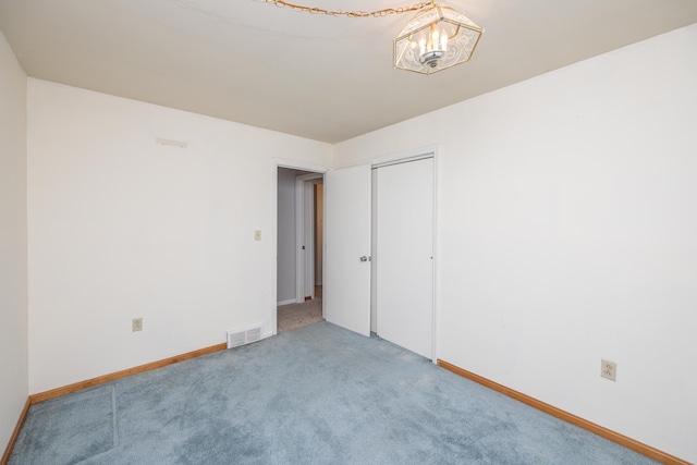 spare room featuring carpet, visible vents, baseboards, and an inviting chandelier