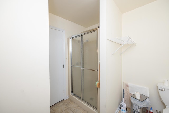 bathroom with a shower stall, toilet, and tile patterned floors