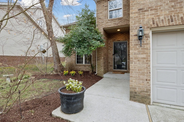 doorway to property with brick siding and an attached garage