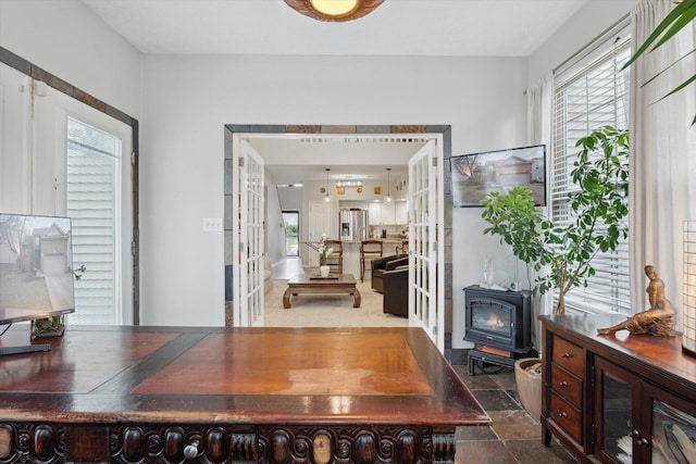 office featuring a wealth of natural light, stone finish floor, and a wood stove