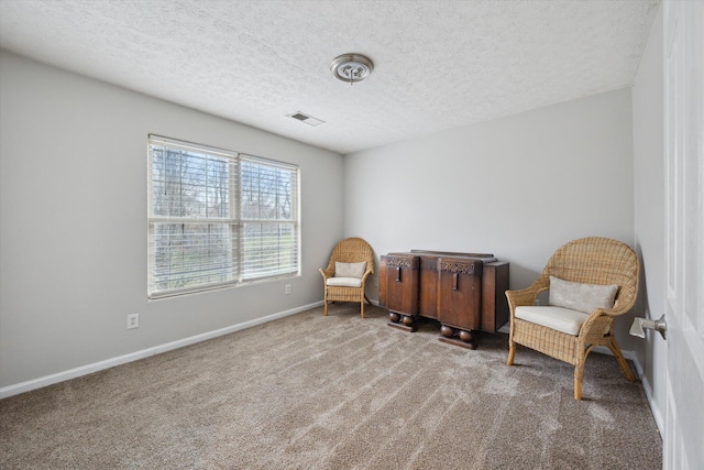 living area with visible vents, carpet floors, a textured ceiling, and baseboards