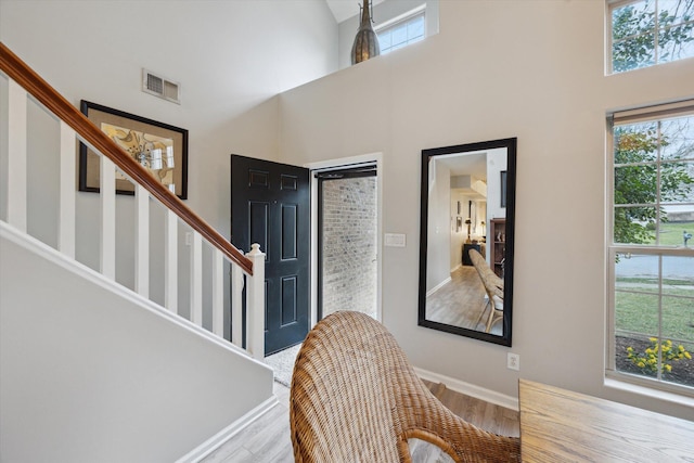 foyer entrance with stairs, wood finished floors, visible vents, and a towering ceiling