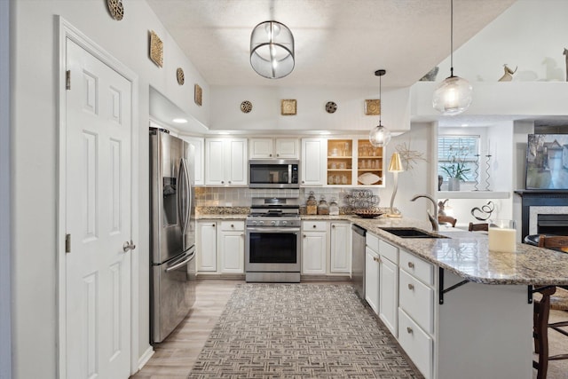 kitchen with a sink, backsplash, appliances with stainless steel finishes, a breakfast bar area, and a peninsula