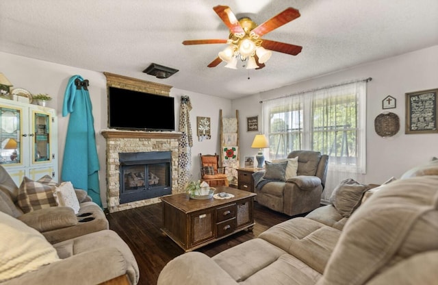 living room with a textured ceiling, a fireplace, dark wood finished floors, and a ceiling fan