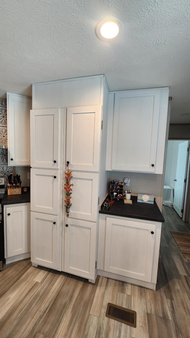 kitchen featuring dark countertops, visible vents, and white cabinets