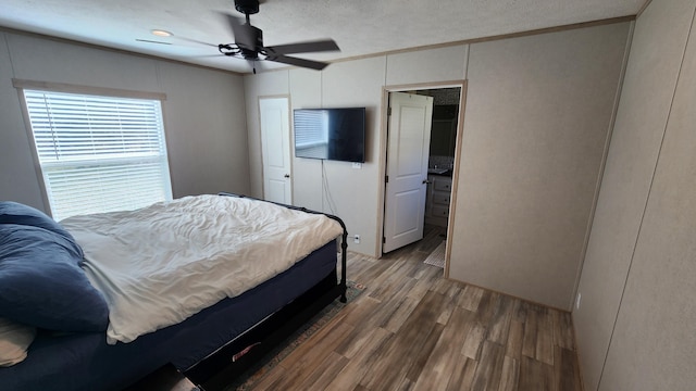 bedroom featuring ornamental molding, a ceiling fan, a textured ceiling, and wood finished floors