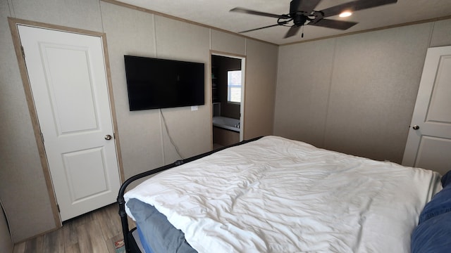 bedroom featuring ornamental molding, ceiling fan, a decorative wall, and wood finished floors