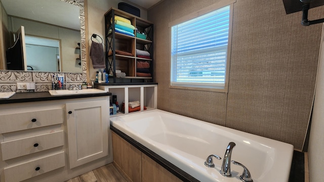 full bath with backsplash, a garden tub, vanity, and wood finished floors