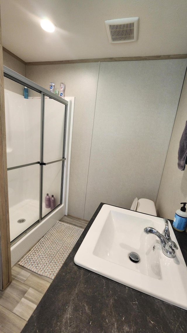 full bath with a stall shower, visible vents, a sink, and wood finished floors