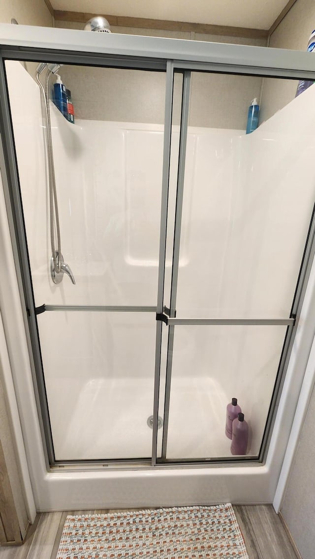 bathroom featuring wood finished floors and a shower stall