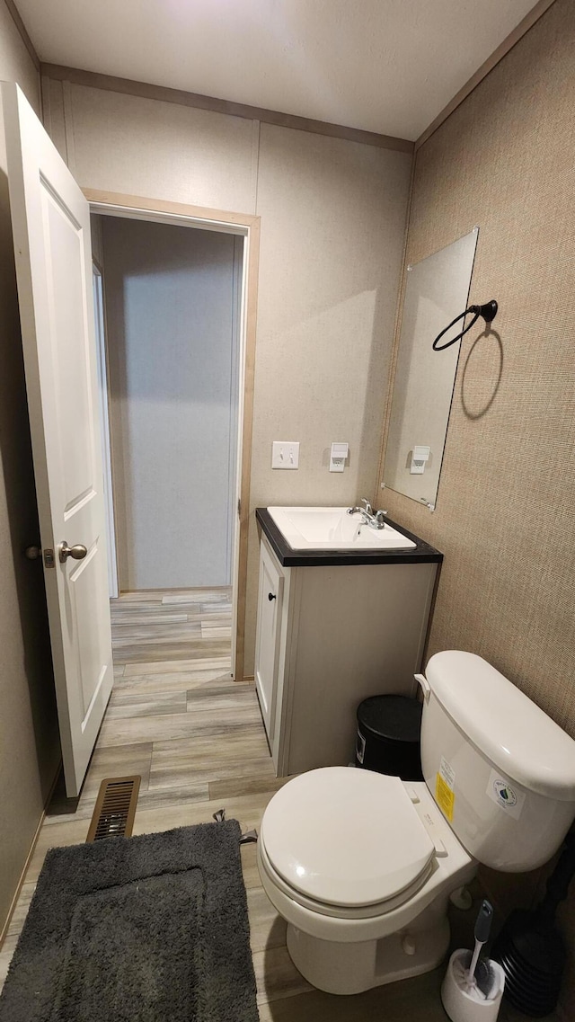 bathroom featuring visible vents, vanity, wood finished floors, and toilet