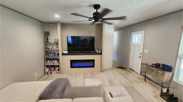 living room featuring a ceiling fan, a glass covered fireplace, and wood finished floors