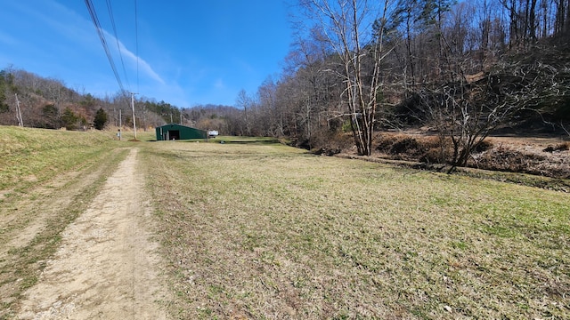 view of road featuring a pole building, a rural view, and a wooded view