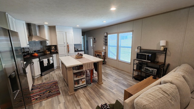 kitchen with a breakfast bar area, decorative backsplash, appliances with stainless steel finishes, light wood-style floors, and wall chimney range hood