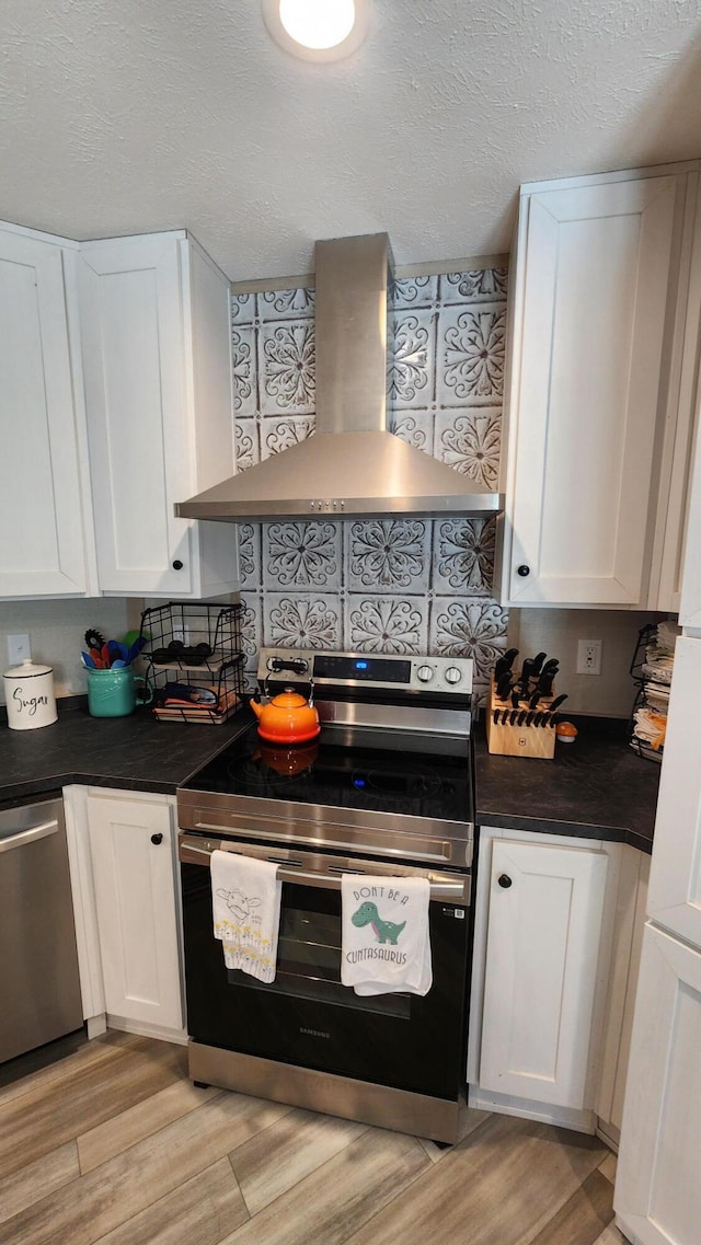 kitchen featuring appliances with stainless steel finishes, white cabinetry, light wood finished floors, and extractor fan