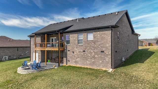 rear view of property featuring a yard, brick siding, a patio area, and a shingled roof