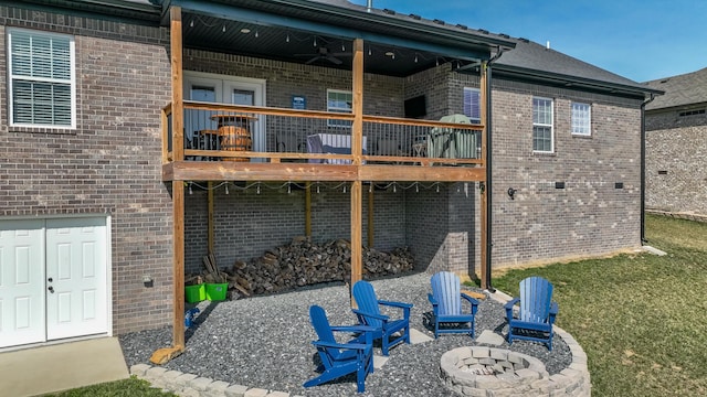 back of house featuring a patio area, an outdoor fire pit, a wooden deck, and brick siding