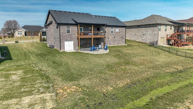 back of house with brick siding, a lawn, a deck, and fence