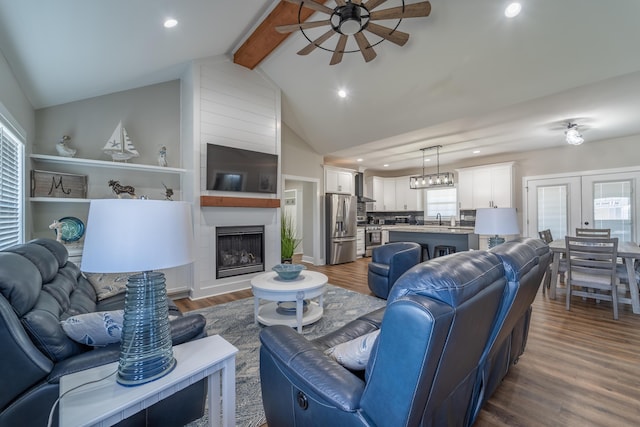 living room featuring a ceiling fan, dark wood-type flooring, a fireplace, beam ceiling, and recessed lighting